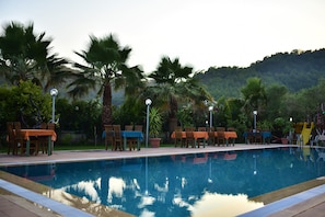 A swimming pool with surrounding palm trees and outdoor seating.