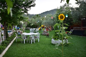 Un jardín cuidado con zona de comedor, mobiliario exterior y un tobogán.