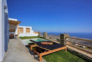 A modern outdoor area with a pool, lounge chairs, and a view of the sea. - Felicia Exclusive Villa - Private Pool (Tinos)