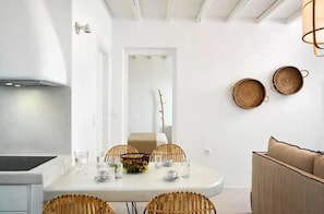 A modern kitchen with a dining area, white walls, and a ceiling with exposed beams. - Felicia Exclusive Villa - Private Pool (Tinos)