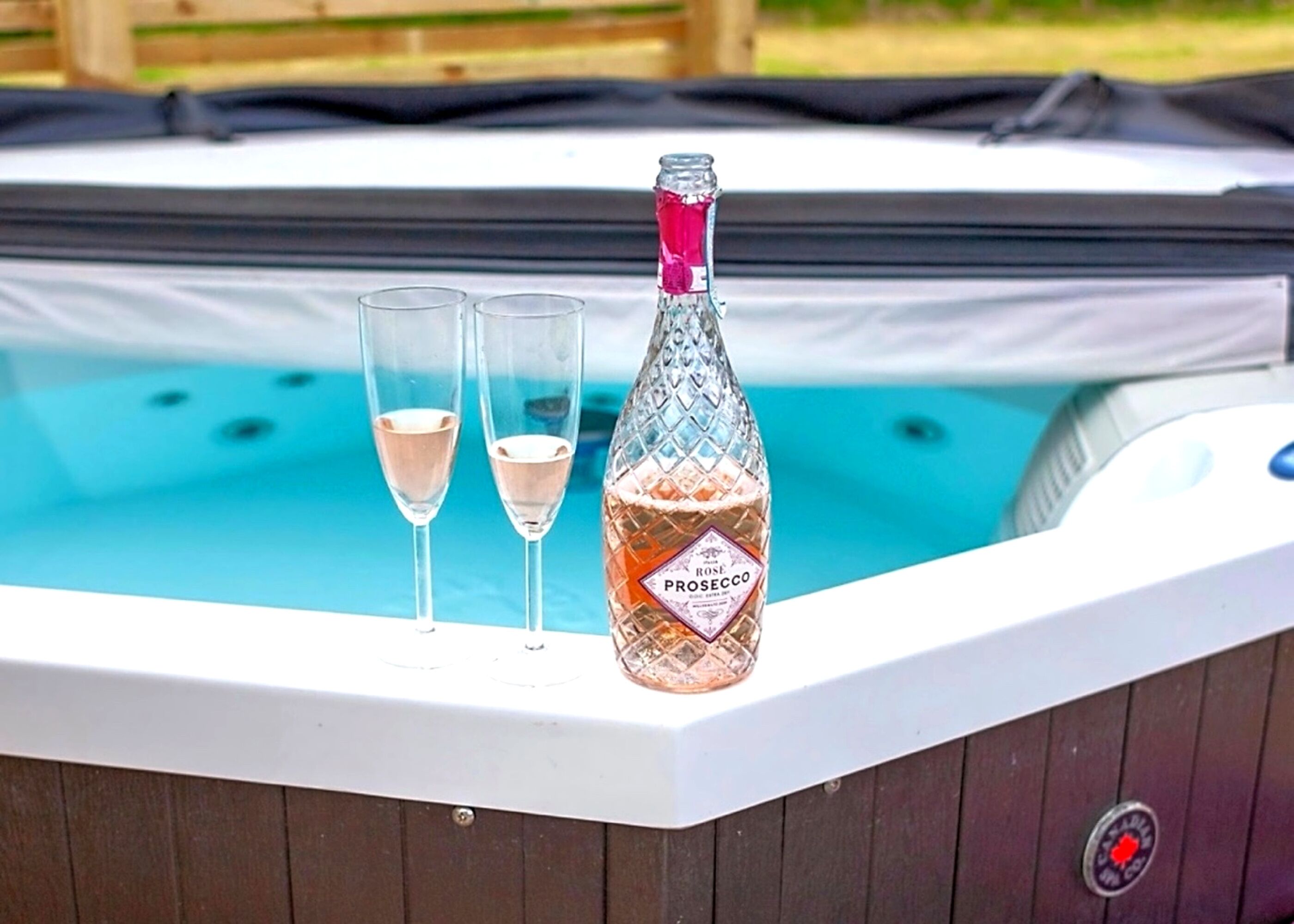 A hot tub with two champagne flutes and a bottle of Rose Prosecco.
