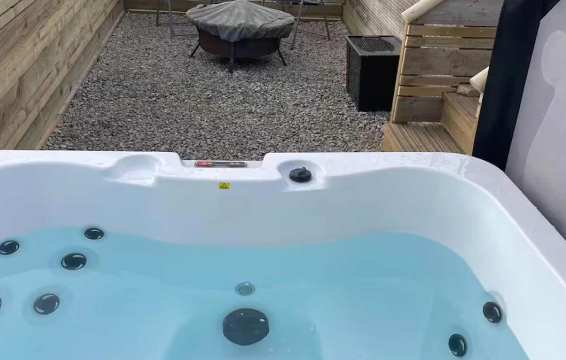 A hot tub with a wooden deck and a covered outdoor seating area.