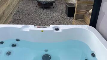 A hot tub with a wooden deck and a covered outdoor seating area.