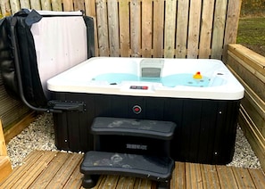 Un jacuzzi con panel de control, un escalón y una bolsa cerca.