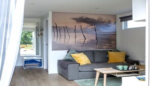 Una sala de estar moderna con un sofá gris, cojines amarillos, una pequeña mesa de madera y un cuadro abstracto grande en la pared.