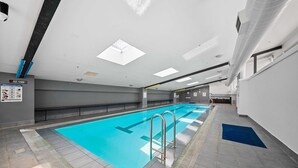 Una piscina con piso azul, pasamanos metálicos y un suelo de baldosas a su alrededor.
