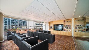 Amplio espacio interior con asientos de cuero negro, alfombra estampada y un ventanal con vistas a edificios.