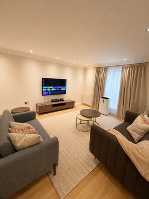 Ein modernes Wohnzimmer mit Flachbildfernseher, Sofas, einem Couchtisch und einem kleinen Beistelltisch.