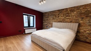 Ein Schlafzimmer mit Holzboden, einem Bett mit Kopfteil, einer Ziegelwand und einem Fenster.