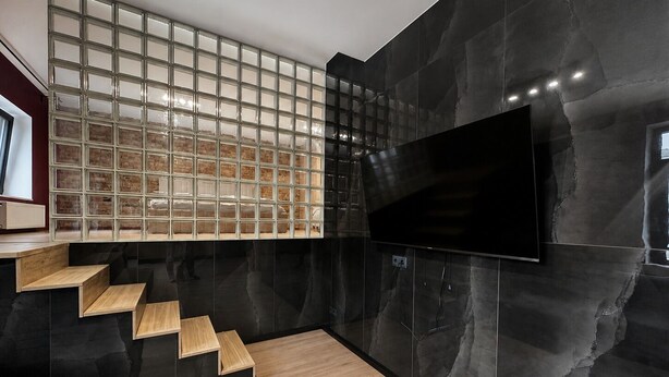 Ein modernes Interieur mit einer Treppe, einem wandmontierten Flachbildfernseher an einer strukturierten Wand und einer Sitzecke.