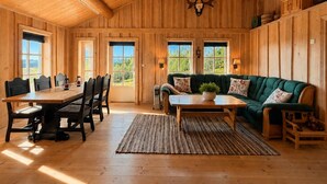 A wooden interior with a dining table, chairs, a sofa, and a fireplace. - Cosy mountain cabin in Golsfjellet (Gol)