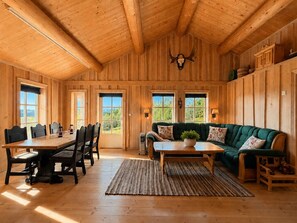 A wooden interior with a dining table, chairs, a sofa, and a fireplace.