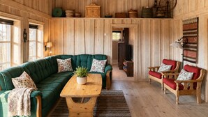 A cozy cabin interior with a green sofa, a wooden table, and a red bench. - Cosy mountain cabin in Golsfjellet (Gol)