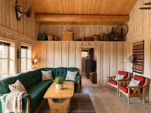A cozy cabin interior with a green sofa, a wooden table, and a red bench.