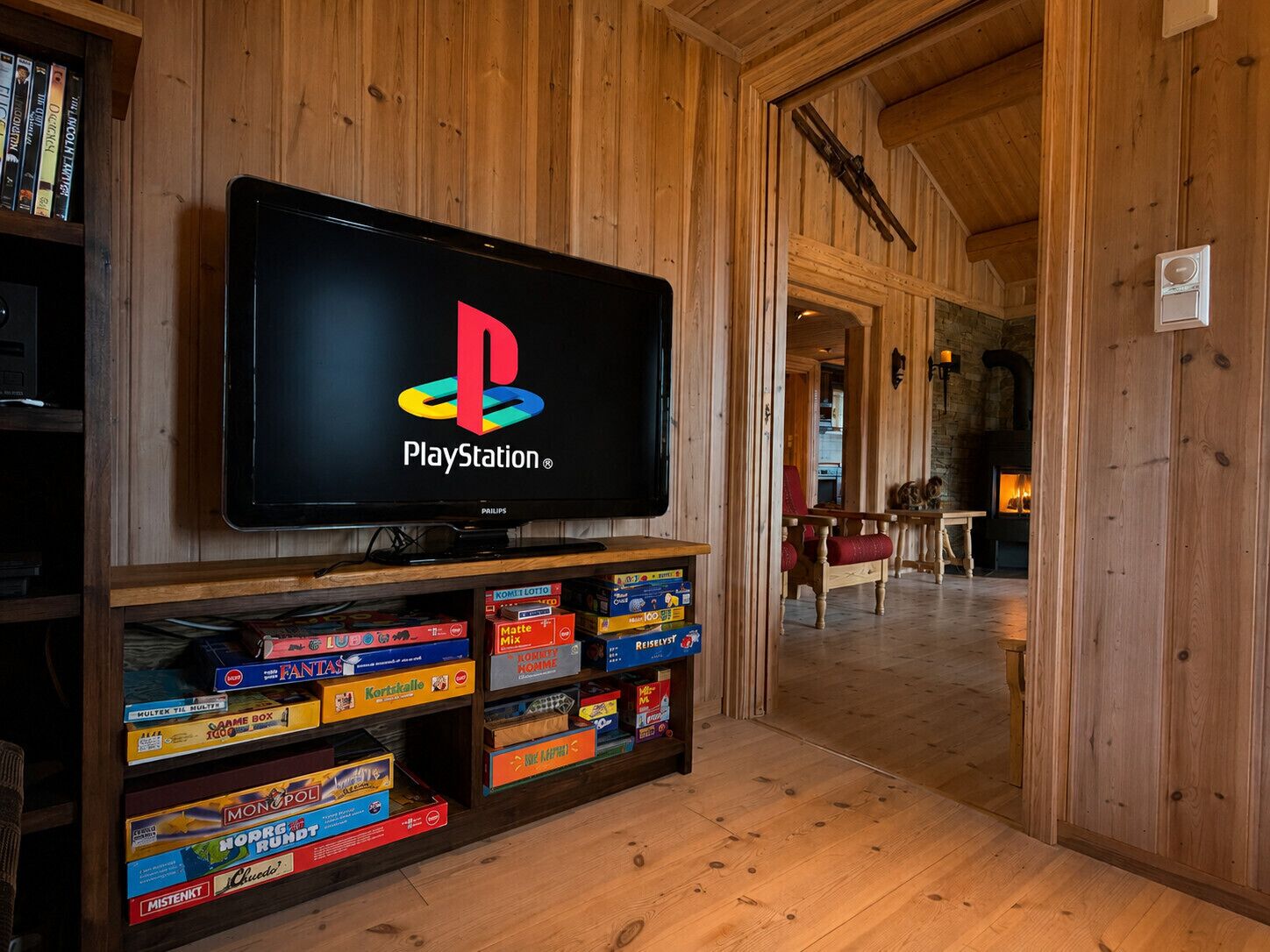 A PlayStation TV mounted on a wooden wall with a shelf below displaying various board games.