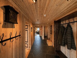 A wooden hallway with a stone floor, coat hooks, and a coat rack.