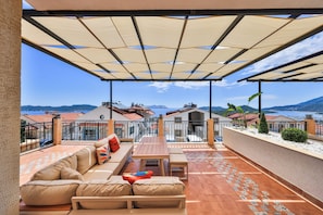 A covered outdoor seating area with a view of the sea and mountains. - AURELİS SUİTES (KAŞ)