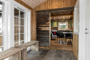 Een houten interieur met een bank, een keuken met groene kastjes, en een eettafel met stoelen.