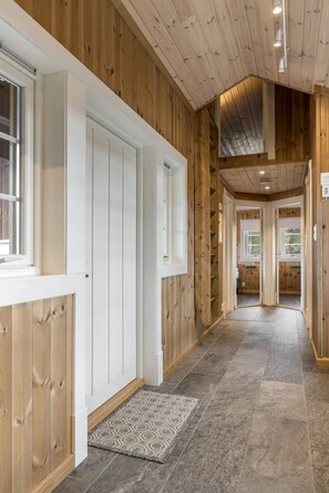 A hallway with wooden walls, a tiled floor, and a door leading to another room.