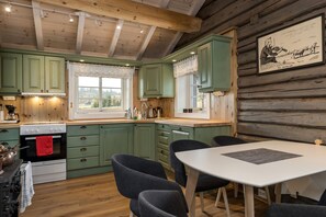 A kitchen with green cabinets, a white stove, and a dining area with a table and chairs.