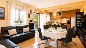 Una sala de estar con sofá, mesa de comedor, sillas y una cocina al fondo.