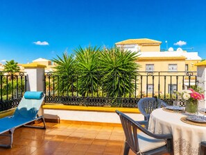 Terrassa amb taula preparada per dinar, una cadira relaxant i una planta decorativa.