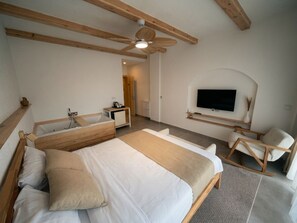 A bedroom with a bed, wooden beams, a ceiling fan, a TV, and a chair. - Jakuzili Deluxe Suite • Vadi Manzaralı • Ardeşen (Rize)