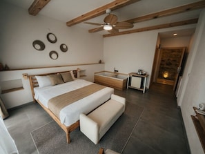 A bedroom with a bed, bench, bedside table, and a ceiling fan.