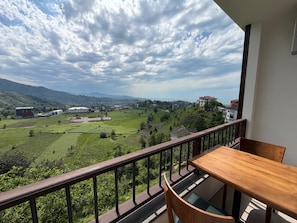 A balcony with a view of a green valley, buildings, and mountains. - Jakuzili Deluxe Suite • Vadi Manzaralı • Ardeşen (Rize)