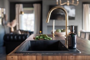 Une cuisine moderne dotée d’un robinet en acier inoxydable, d’un plan de travail en bois et d’une bouteille d’huile d’olive.