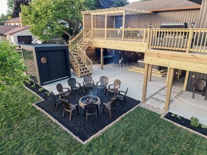 A backyard with a deck, outdoor seating, and a fire pit.