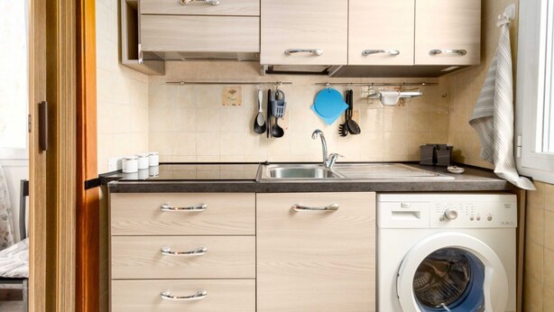 A compact kitchen with a built-in washing machine, wooden cabinets, and a tiled backsplash. - Guesthost - N&D Studio Modena Center (Modena)