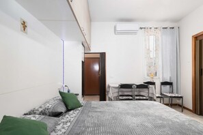 Une chambre Ă coucher avec un lit, un bureau, une chaise et une porte.