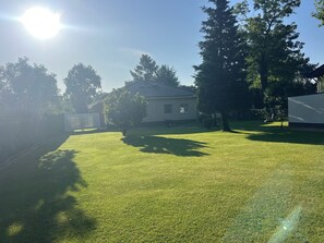 Une pelouse bien entretenue, avec une maison, des arbres et un ciel dégagé.