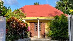 Une maison avec un toit rouge, des portes en bois et une véranda couverte.