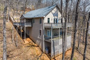 A two-story cabin with a balcony, surrounded by trees.
