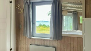 Ein Zimmer mit Fenster, Holzwänden, Heizkörper und Bett.