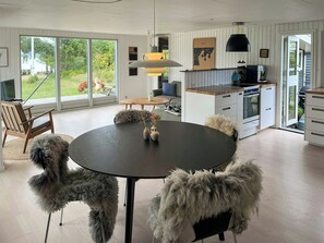 Une cuisine moderne avec un coin repas, de grandes fenêtres et une vue sur l’extérieur.