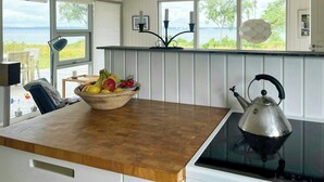 Eine Küche mit einer Holzausziehtafel, einem Wasserkocher und einer Obstschale.