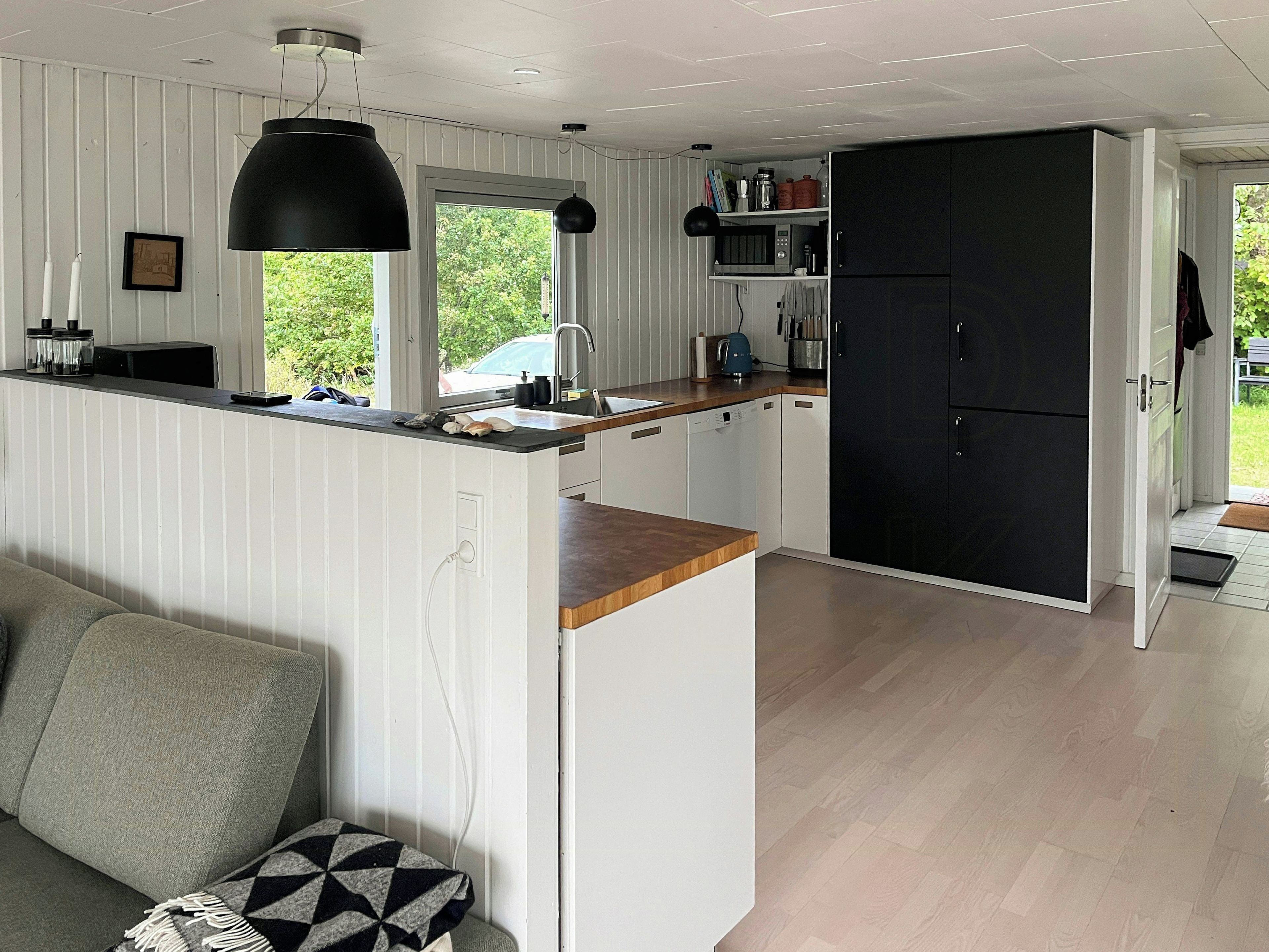 A modern kitchen with a black refrigerator, white cabinetry, and a wooden countertop.