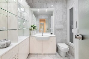 Ein modernes Badezimmer mit einem мраморной раковиной, Toilette und einer Duschkabine aus Glas.