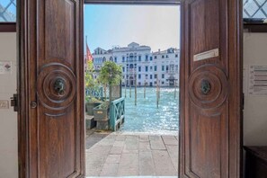 A wooden door leading to a canal with buildings in the background. - Spacious Apartment Near Rialto & Santa Croce with Grand Canal Views (Venezia)