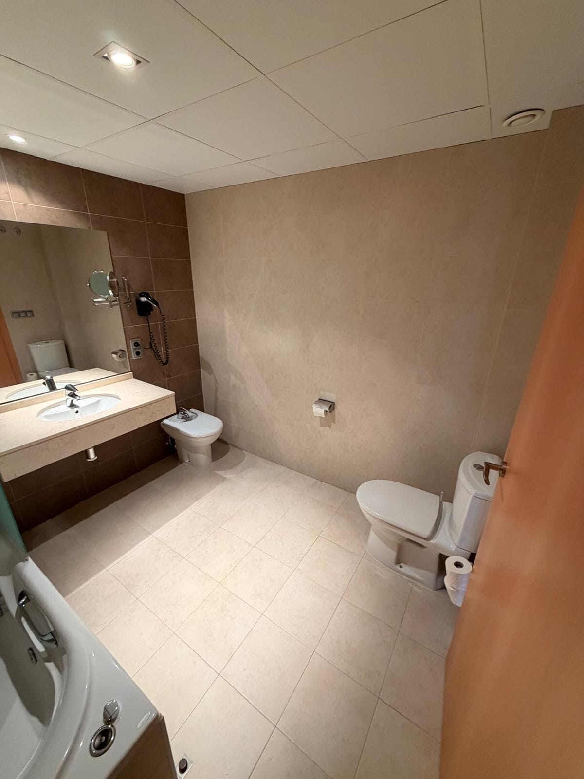 Un baño moderno con lavamanos, inodoro y ducha.