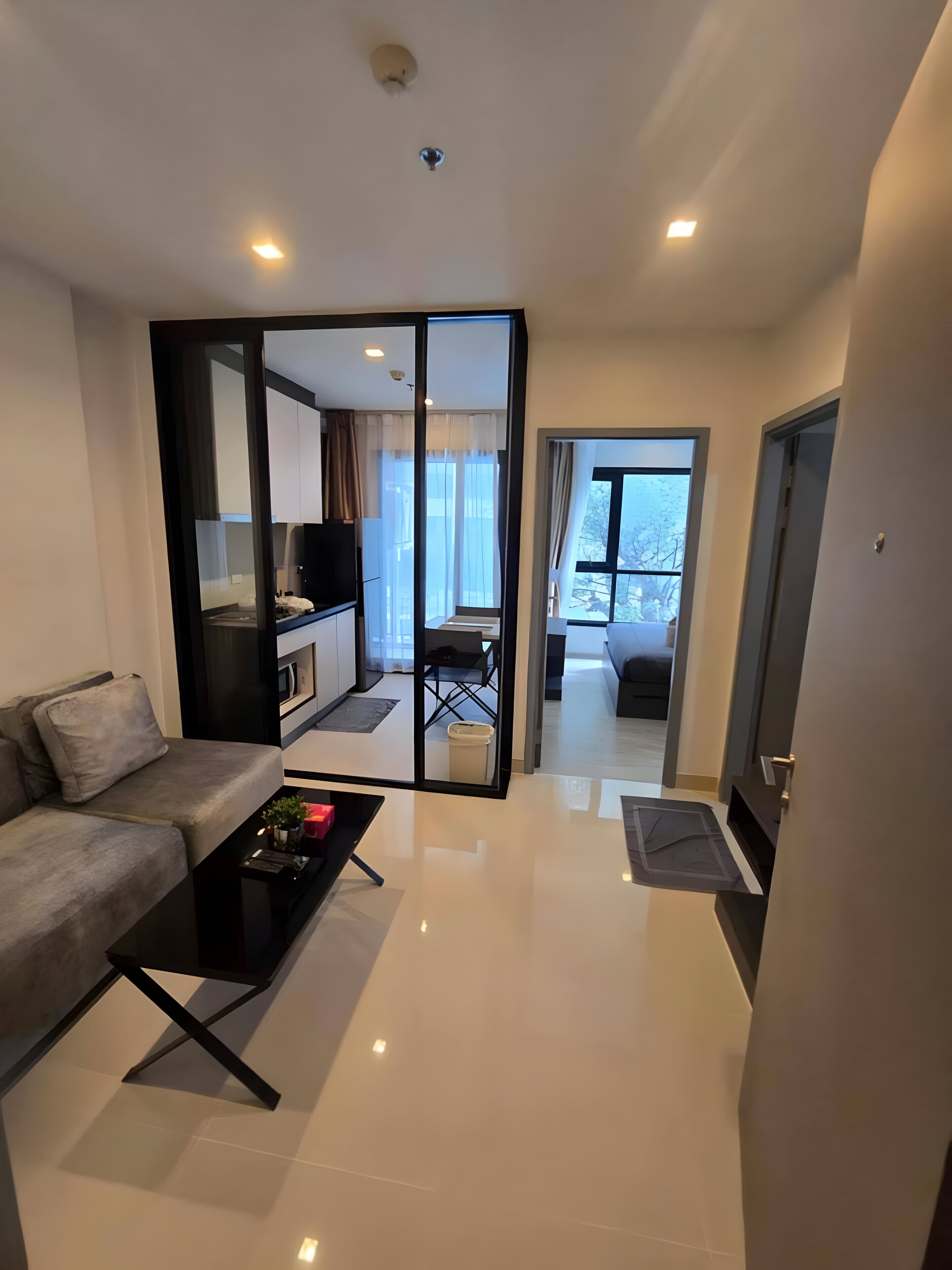 Una sala de estar moderna con un sofá, una mesa de centro y un ventanal corredero que da a un balcón.