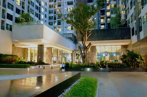 Un edificio moderno con un patio central, un árbol y una fuente de agua reflectante.