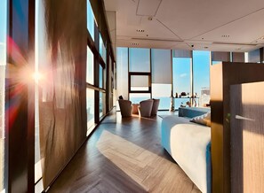 A modern hotel room with large windows, a bed, a seating area, and a view of the city. - The Base Central Pattaya - Rooftop Pool (Muang Pattaya)