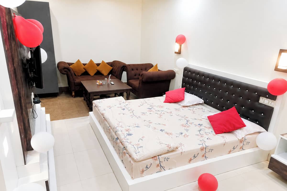 A bedroom with a bed, a sofa, a table, and a television.