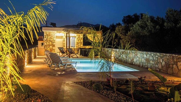 Un edificio in pietra con piscina, area relax all'aperto e un muro di pietra.