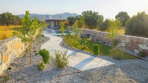Un'area esterna curata con aiuole, un muro in pietra, un vialetto sinuoso e un edificio con tetto spiovente.