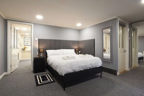A modern bedroom with a large bed, bedside tables, a mirror, and a carpeted floor. - Clarence Cottage | 4mins to Pier, Pet Friendly with Shared Garden (Portsmouth)
